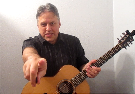 Guitar Lessons, Free Sample Video Links, Tablature, Tips and Updates Dennis Hartman, snaring, holding the guitar and pointing at the reader